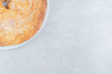 Beyaz tabakta pudrayla süslenmiş yuvarlak pasta. Yüksek kalite fotoğraf