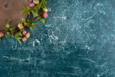 Mavi arka planda, tahtanın etrafında çiçekler var. Yüksek kalite fotoğraf