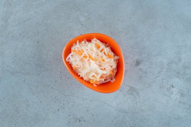 Mavi arka planda plastik kasede havuçlu mayalanmış lahana turşusu. Yüksek kalite fotoğraf