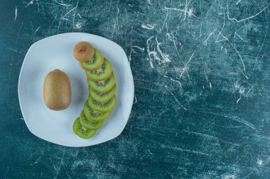  Dilimlenmiş ve tüm kivi tabakta, mermer zemin üzerinde. Yüksek kalite fotoğraf