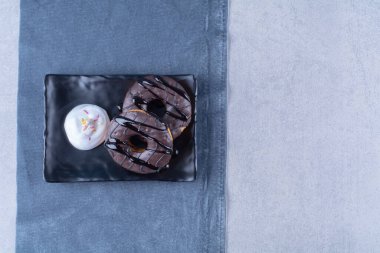 Masa örtüsü üzerinde siyah bir tabak çikolatalı çörek. Yüksek kalite fotoğraf