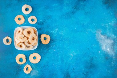 Mavi arka planda, bir kasede kurumuş elma halkaları. Yüksek kalite fotoğraf