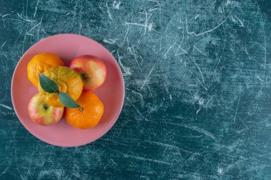 Elmalar ve mandalinalar bir tabakta, mermer arka planda. Yüksek kalite fotoğraf