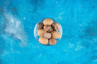 Mavi arka planda cam bir kasede cevizler. Yüksek kalite fotoğraf