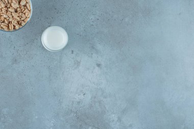 Mermer zemin üzerinde, cam bir kaidede mısır gevreğinin yanında bir bardak süt. Yüksek kalite fotoğraf