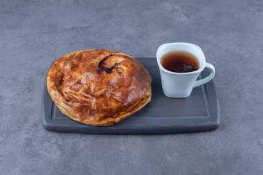 Bir fincan çay ve mermer zemin üzerinde, ahşap tepside tatlı bir turta. Yüksek kalite fotoğraf