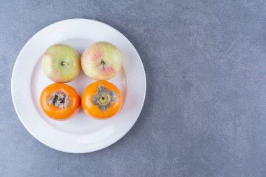Hurma ve elma tabakta, mermer arka planda. Yüksek kalite fotoğraf