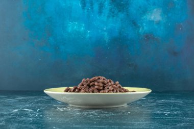 Mavi arka planda bir tabak çikolatalı mısır halkası. Yüksek kalite fotoğraf