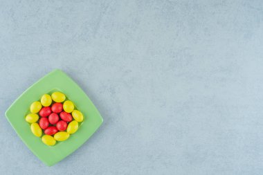 Beyaz arka planda tatlı sarı ve kırmızı şekerli yeşil bir tabak. Yüksek kalite fotoğraf