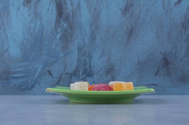 Gri arka planda şekerle dolu yeşil bir tabak. Yüksek kalite fotoğraf