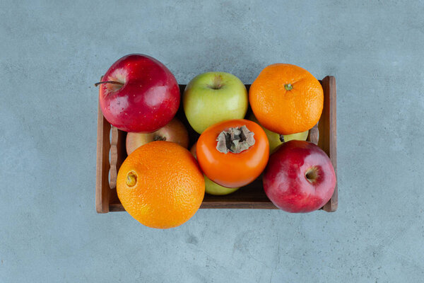 Различные фрукты в коробке, на мраморном фоне. Высокое качество фото