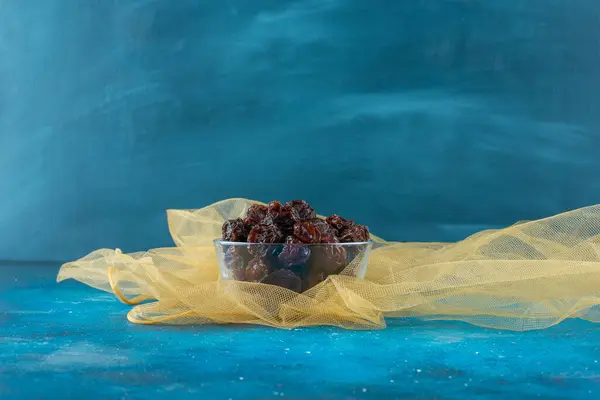 A glass of dried plums on tulle , on the blue background. High quality photo