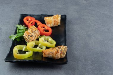 Et ve sebzeyle doldurulmuş siyah tabakta dilimlenmiş çörek. Yüksek kalite fotoğraf