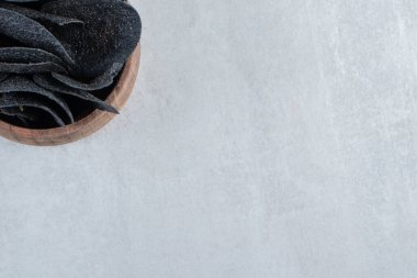 Tahta arka planda çıtır çıtır siyah cips kasesi. Yüksek kalite fotoğraf