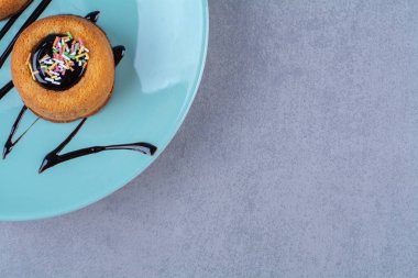 Renkli şekerli iki tatlı donuttan oluşan mavi bir tabak. Yüksek kalite fotoğraf