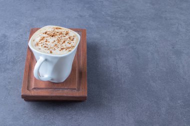 Dilimlenmiş limonun yanındaki ahşap tabakta bir fincan kapuçino, mavi arka planda. Yüksek kalite fotoğraf