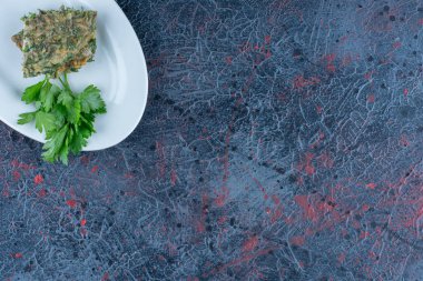 Otlu ve dilimlenmiş domatesli beyaz bir tabak omlet. Yüksek kalite fotoğraf