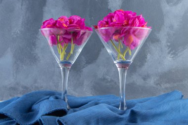 Beyaz arka planda, bir kumaş parçasında bir bardakta taze mor çiçekler. Yüksek kalite fotoğraf