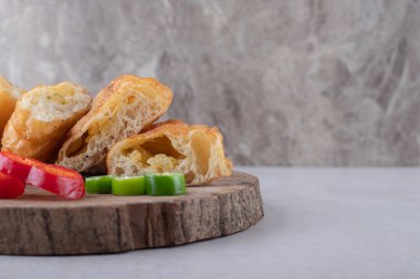 Güvertede dilimlenmiş pirozhki ve biber, mermer arka planda. Yüksek kalite fotoğraf