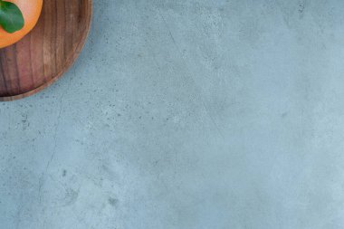 Tahta bir tabakta, mermer zemin üzerinde olgun, sulu bir portakal. Yüksek kalite fotoğraf