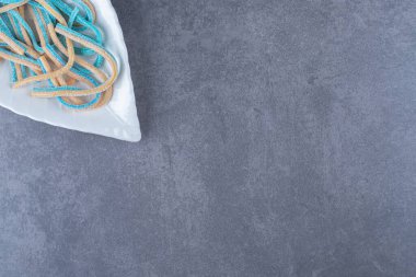 İki renkli halat şeklinde şekerler bir tabakta, mermer arka planda. Yüksek kalite fotoğraf