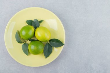 Sarı tabakta yaprakları olan lezzetli limon meyveleri. Yüksek kalite fotoğraf