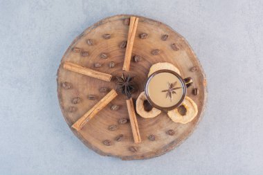 Tahta parçasında tarçın çubukları olan bir fincan sıcak kahve. Yüksek kalite fotoğraf