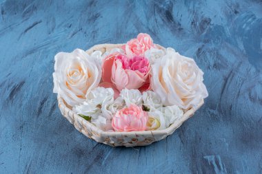 Hasır sepette mavi arka planda güzel renkli bir gül çiçeği. Yüksek kalite fotoğraf