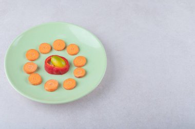 Kumquat, dilimlenmiş biber ve dilimlenmiş havuç tabakta, mermer zemin üzerinde. Yüksek kalite fotoğraf