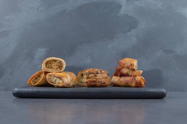 Karanlık tahtada bir sürü doldurulmuş hamur işi var. Yüksek kalite fotoğraf