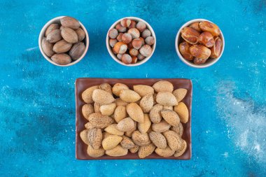 Kabuklu fındıklar tabakta ve kaselerde, mavi arka planda. Yüksek kalite fotoğraf