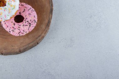 Ahşap parçasına serpiştirilmiş pembe ve beyaz çörekler. Yüksek kalite fotoğraf