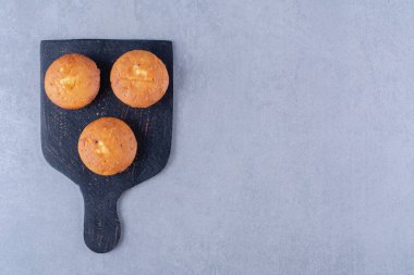 Üç tatlı taze kekten oluşan siyah ahşap bir tahta. Yüksek kalite fotoğraf