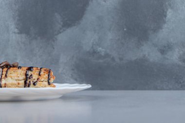 Beyaz tabağa yerleştirilmiş çikolata şurubuyla süslenmiş tatlı pasta. Yüksek kalite fotoğraf