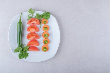 Havuçta kırmızı biber, tabakta domateslerin yanında, mermer zemin üzerinde. Yüksek kalite fotoğraf