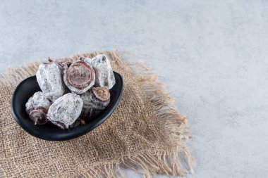 Mermer arka planda siyah bir kâse kurutulmuş hurma. Yüksek kalite fotoğraf