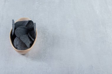 Taş zeminde bir kase tuzlanmış siyah cips. Yüksek kalite fotoğraf