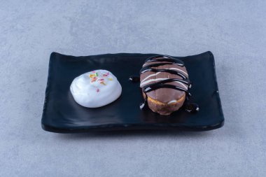 Masa örtüsü üzerinde siyah bir tabak çikolatalı çörek. Yüksek kalite fotoğraf