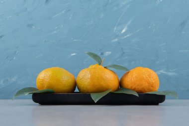 Siyah tabakta yaprakları olan taze mandalina. Yüksek kalite fotoğraf