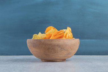 Tahta arka plandaki ahşap kaseye yerleştirilmiş lezzetli çıtır cipsler. Yüksek kalite fotoğraf