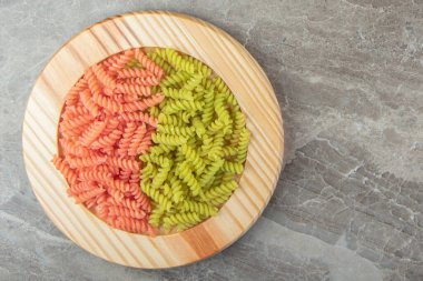 Tahta tabakta çiğ yeşil ve kırmızı fusilli. Yüksek kalite fotoğraf