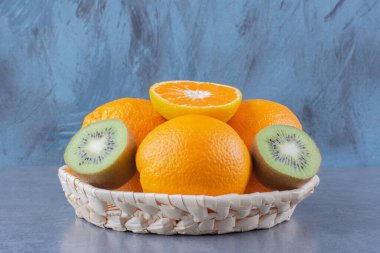 Portakal ve kivi meyveleri sepetin içinde, mermer arka planda. Yüksek kalite fotoğraf