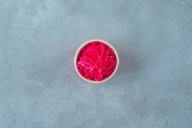 Lezzetli mayalanmış kırmızı lahana mavi arka planda bir kasede yatıyor. Yüksek kalite fotoğraf