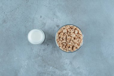 Mermer zemin üzerinde, cam bir kaidede mısır gevreğinin yanında bir bardak süt. Yüksek kalite fotoğraf