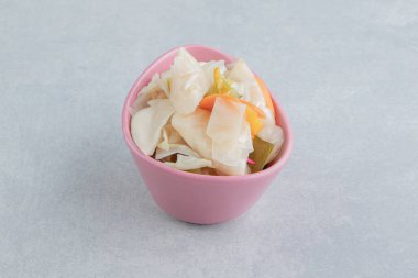 Mermer arka planda, kâsede lezzetli sebze turşusu. Yüksek kalite fotoğraf