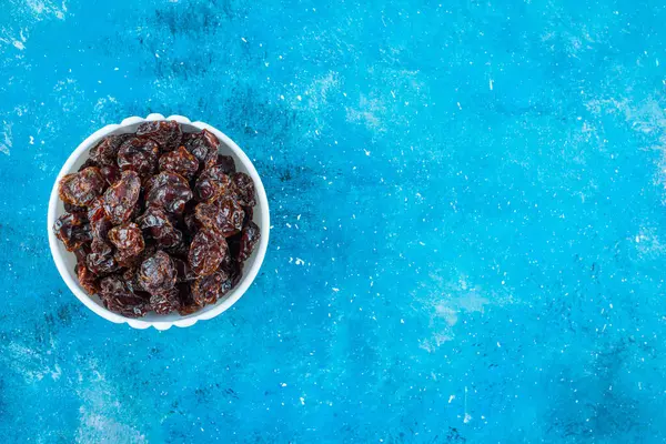 Toothsome dried plums in a bowl , on the blue background. High quality photo