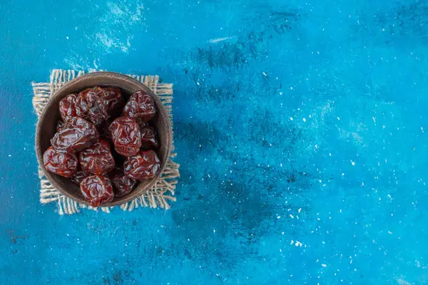 Dried plums in a bowl on texture , on the blue background. High quality photo