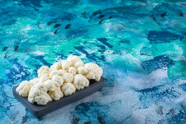 Mavi arka planda, tahta bir tabakta karnabahar. Yüksek kalite fotoğraf