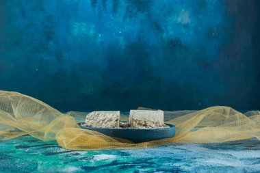 Soyulmuş ayçekirdeği ve dilimlenmiş halva tülün üzerindeki ahşap tabakta, mavi arkaplanda. Yüksek kalite fotoğraf