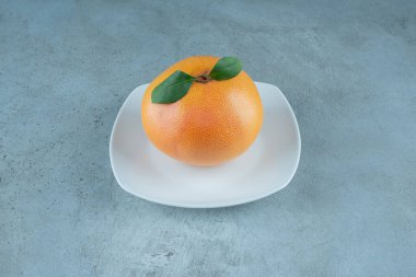 Lezzetli bir portakal tabakta, mermer arka planda. Yüksek kalite fotoğraf